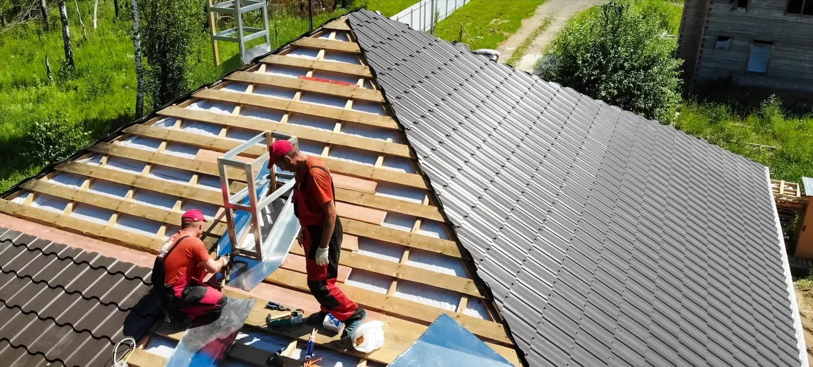 Two men are working on the roof of a house.