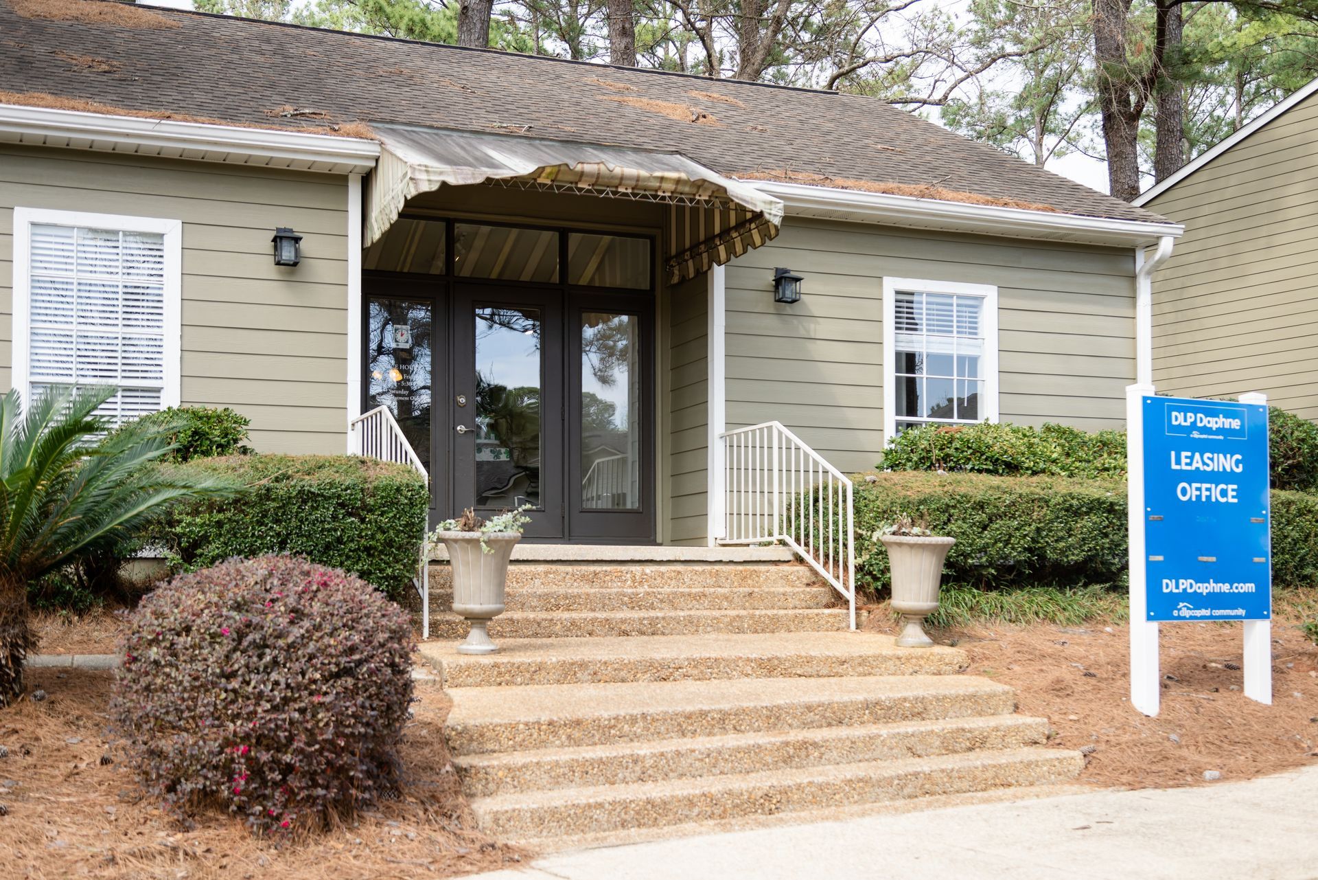 Apartment leasing office exterior, light green building with steps, awning, and sign.