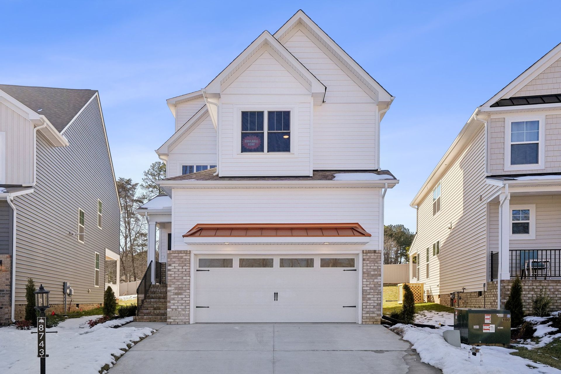 A white house with a garage and a driveway in front of it
