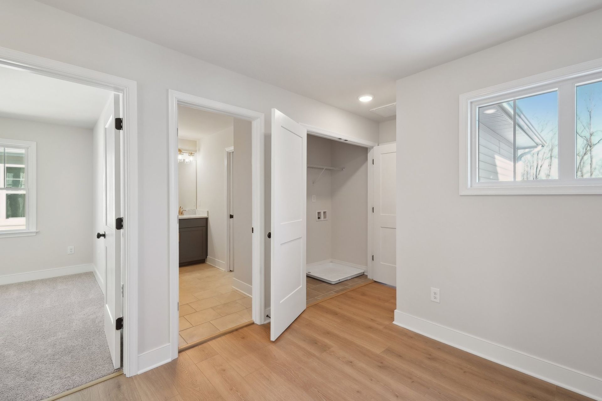 An empty bedroom with hardwood floors and white walls.