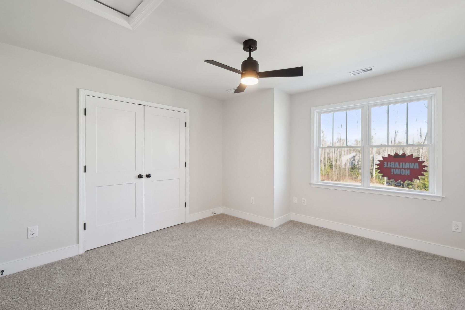An empty bedroom with a ceiling fan and a window.