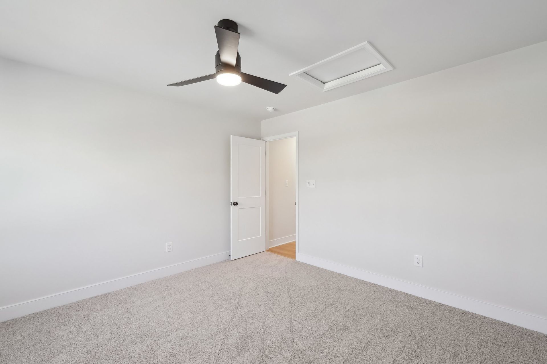 An empty bedroom with a ceiling fan and a door.