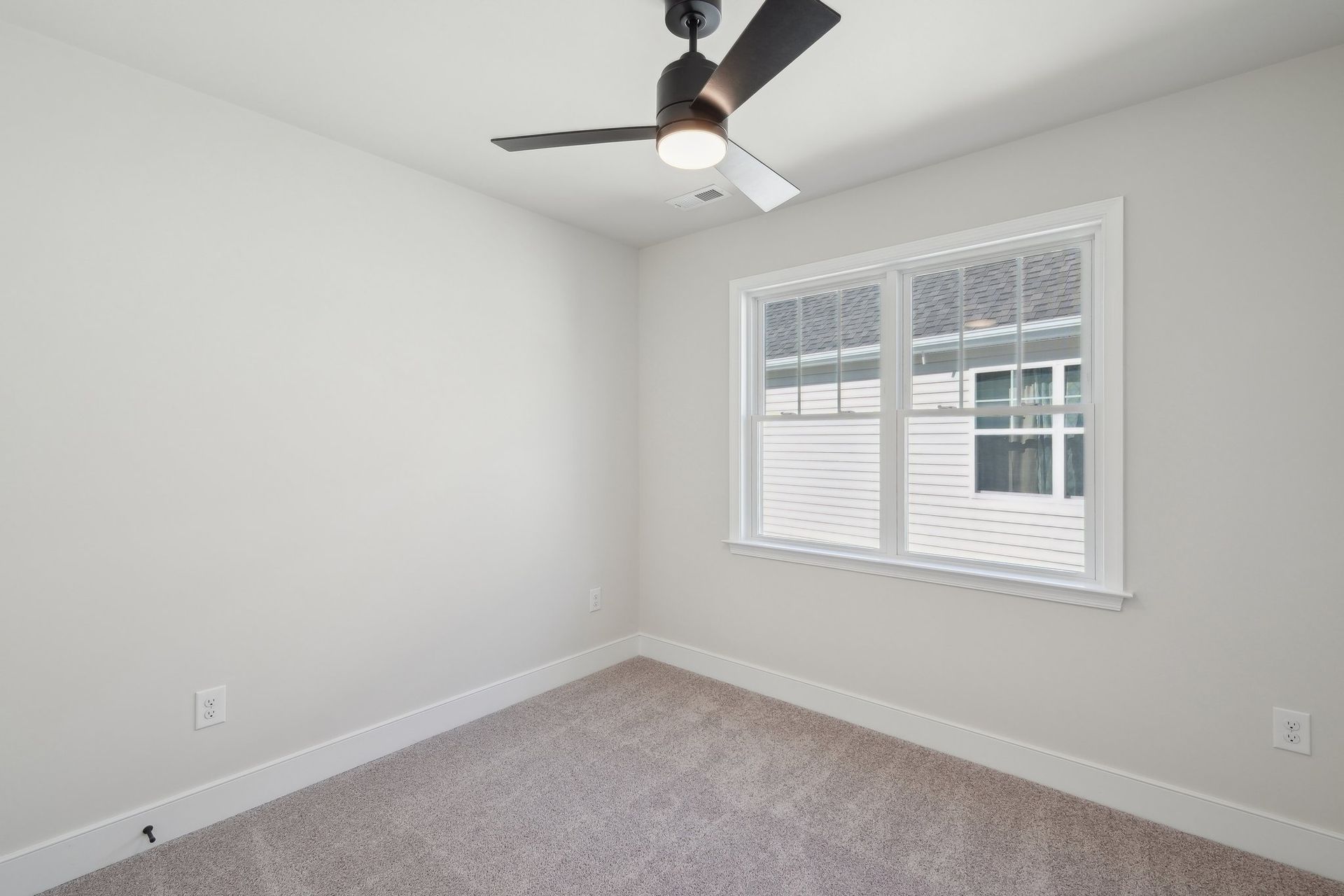 An empty bedroom with a ceiling fan and a window.