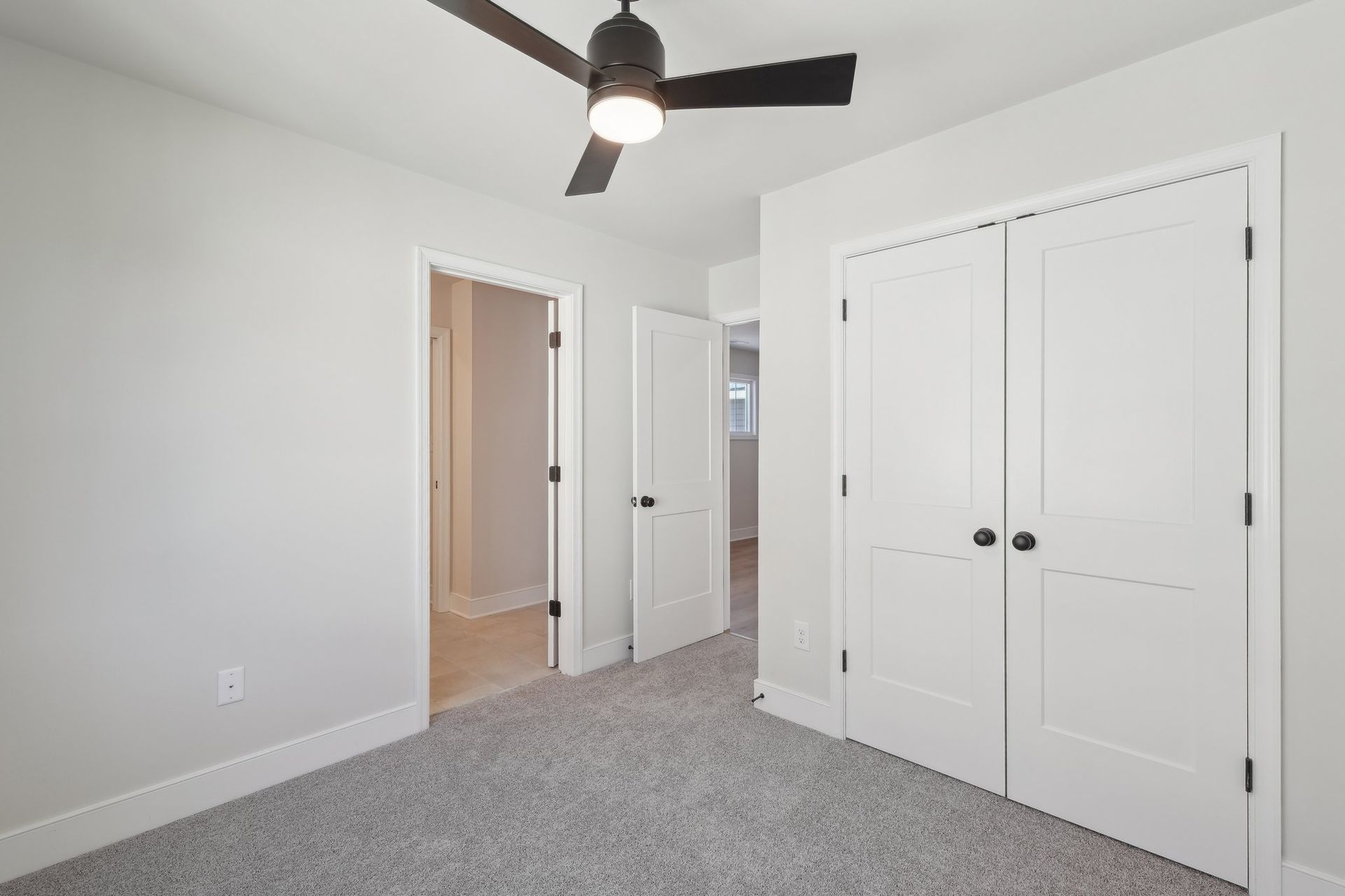 An empty bedroom with a ceiling fan and a closet.
