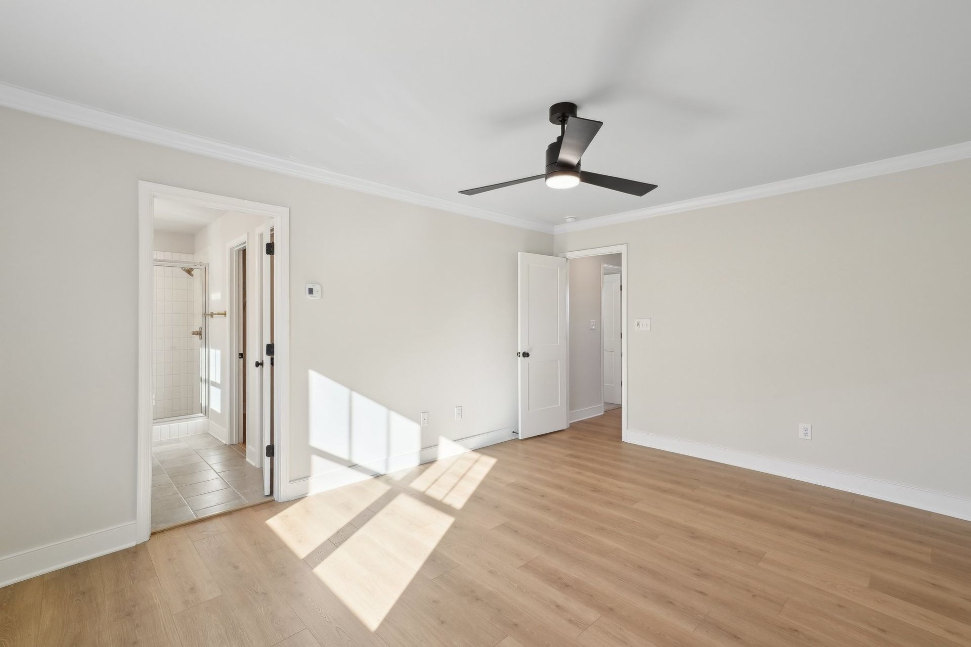 An empty room with hardwood floors and a ceiling fan.