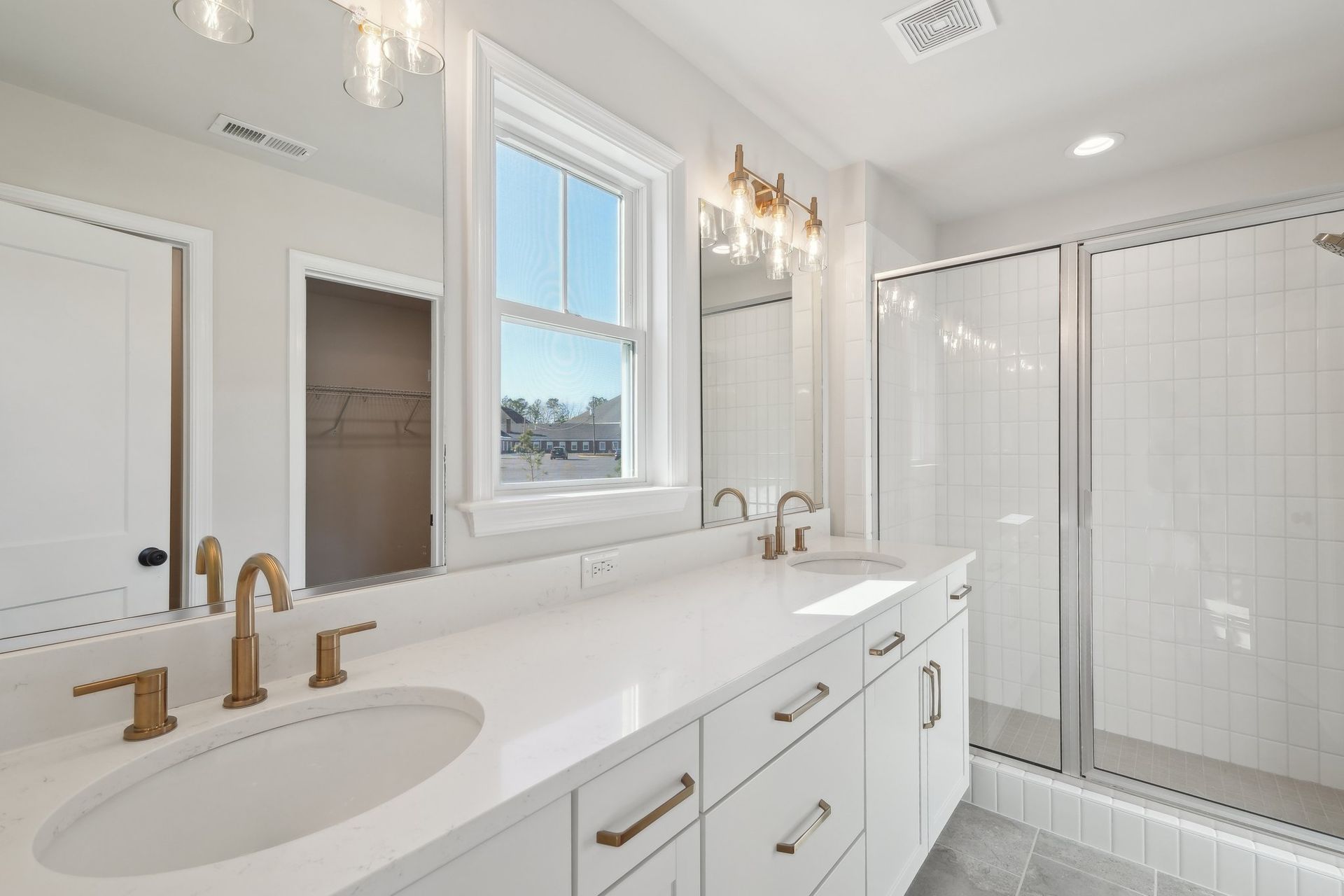 A bathroom with two sinks , a shower and a window.