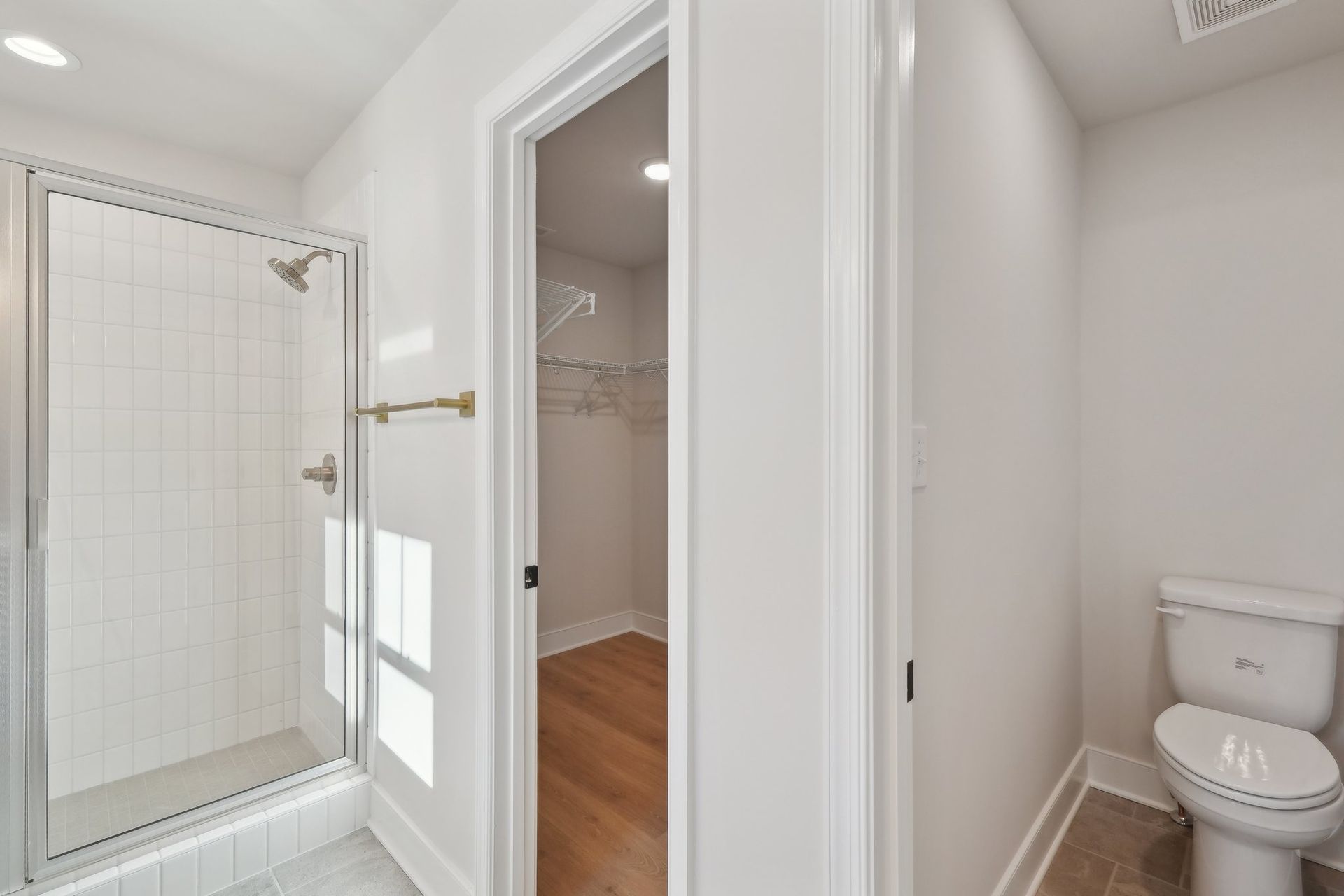 A bathroom with a toilet , shower and walk in closet.