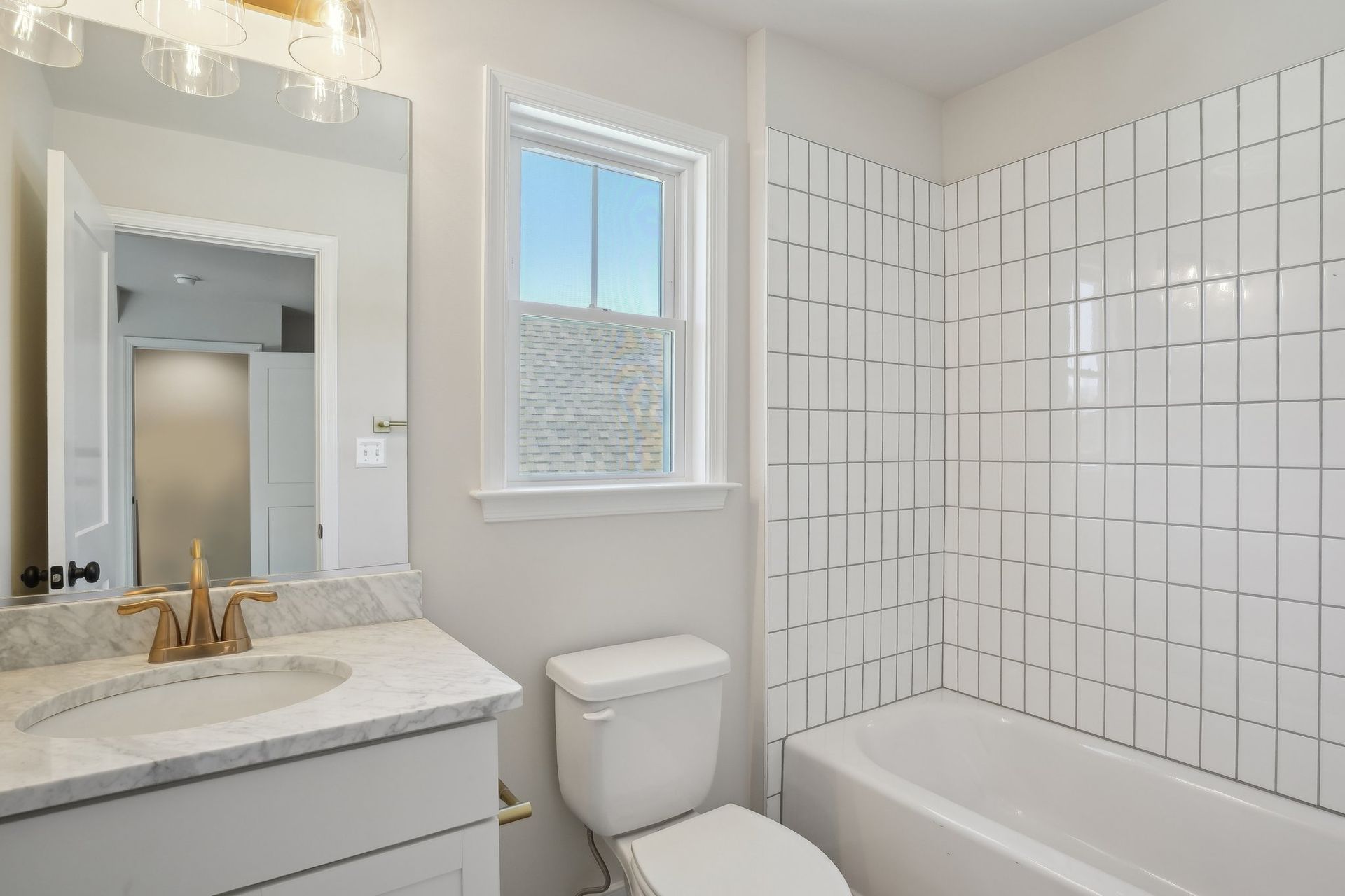 A bathroom with a toilet , sink , tub and mirror.
