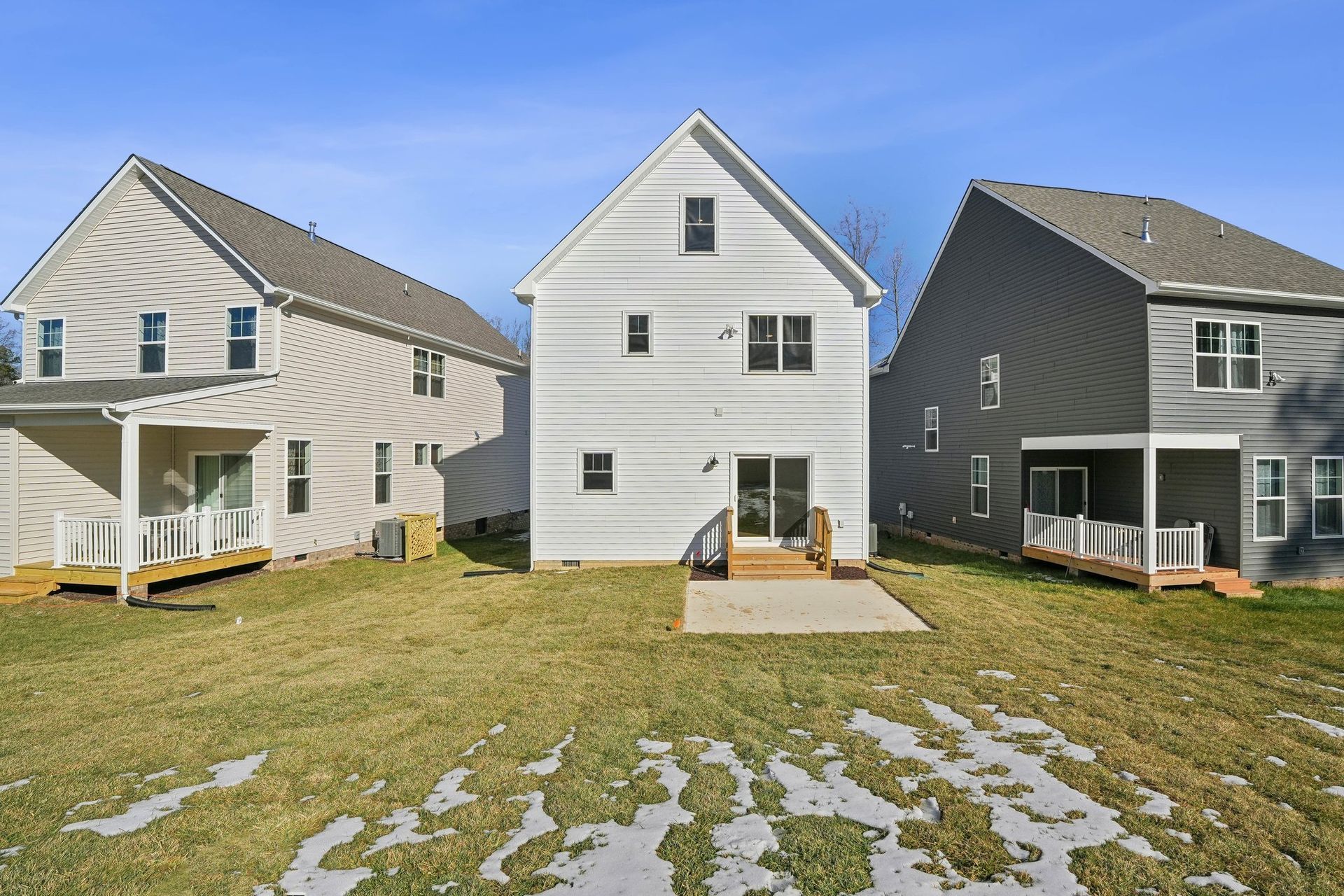 Three houses are sitting next to each other on a lush green field.