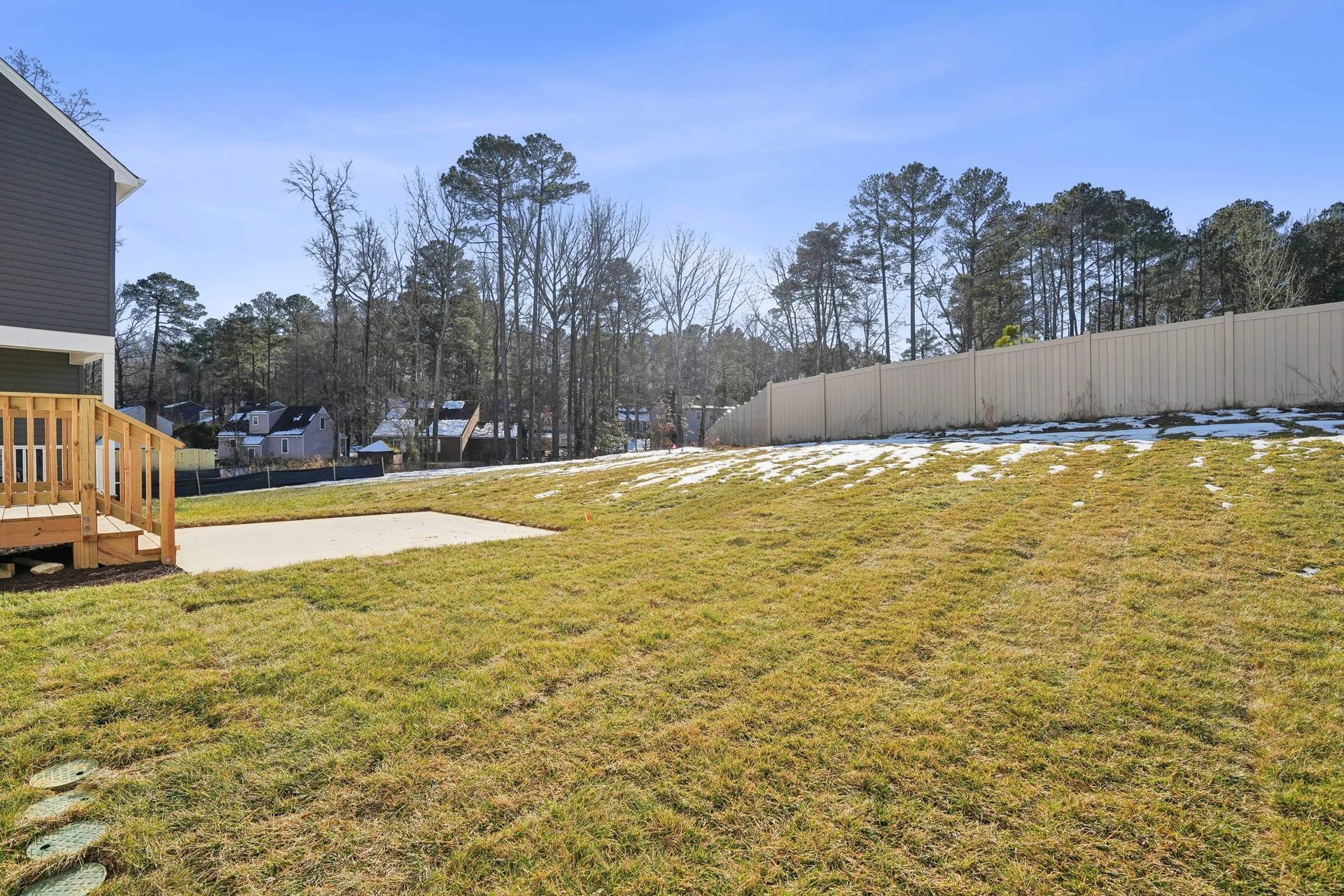 A large grassy yard with a fence and a house in the background.