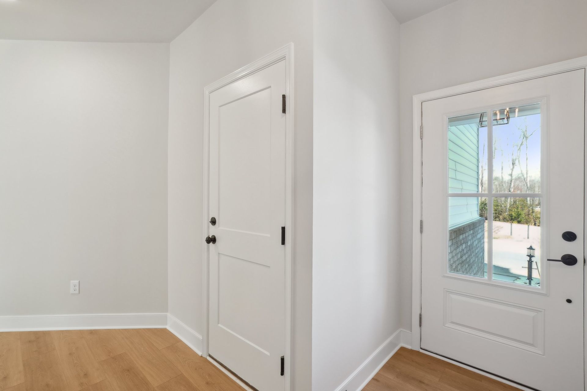 A hallway with two white doors and a window.