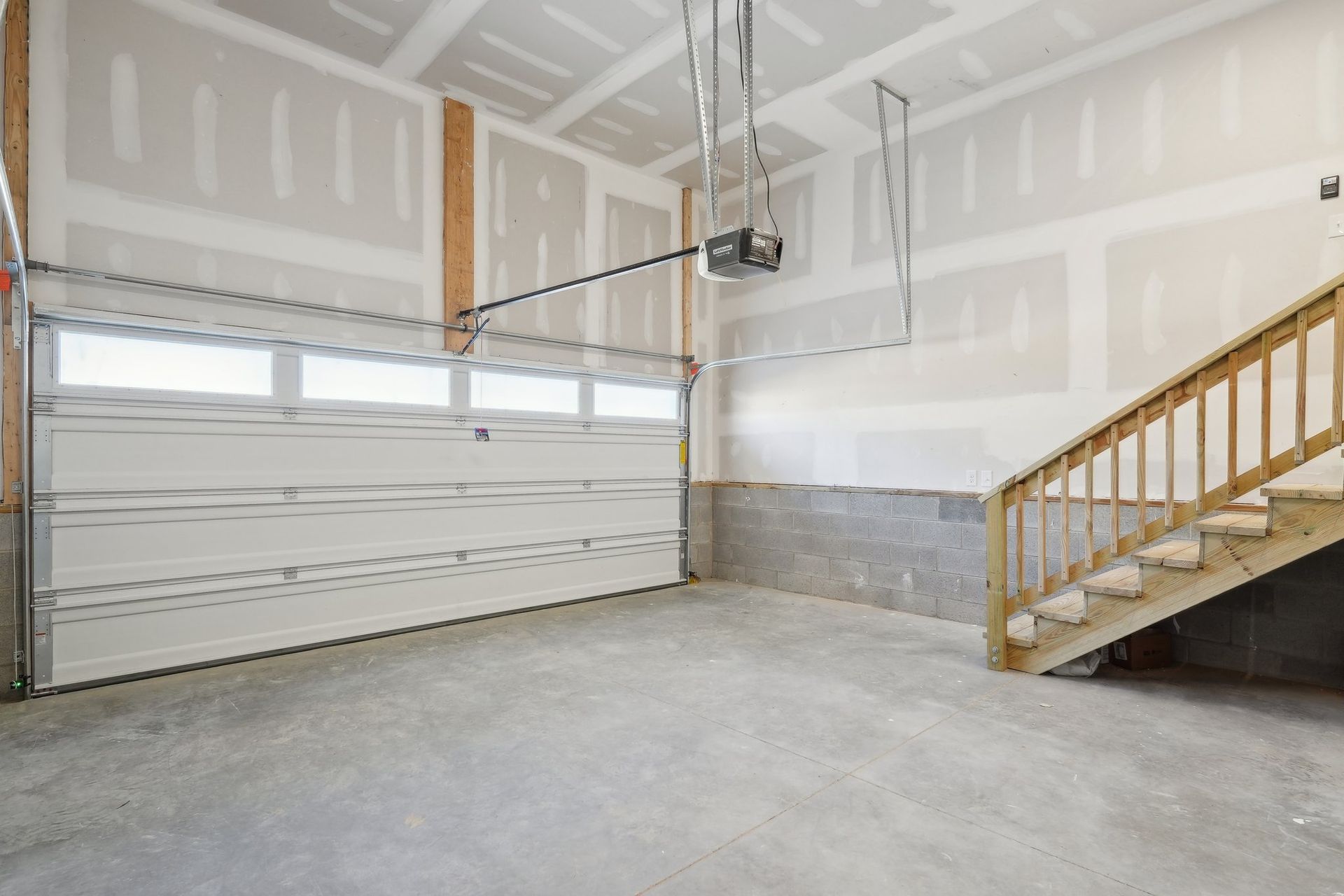 An empty garage with stairs and a garage door open.