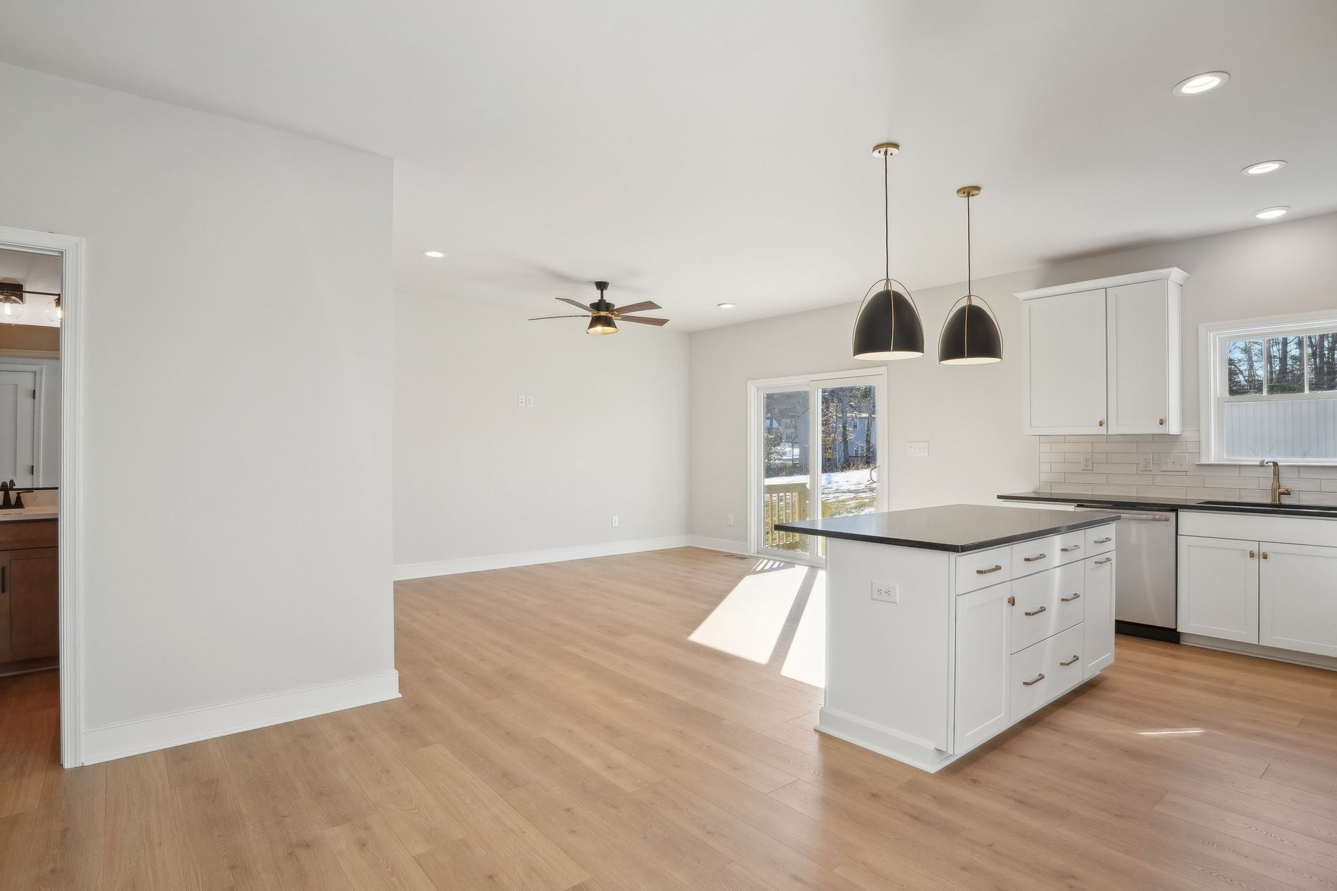 An empty kitchen with white cabinets and a large island.