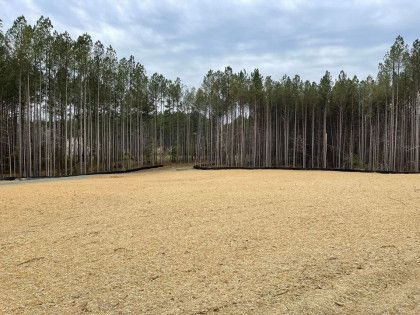 A gravel road with trees in the background and a car parked in the middle of it.