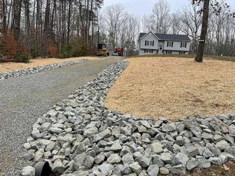 A gravel road with trees in the background and a car parked in the middle of it.