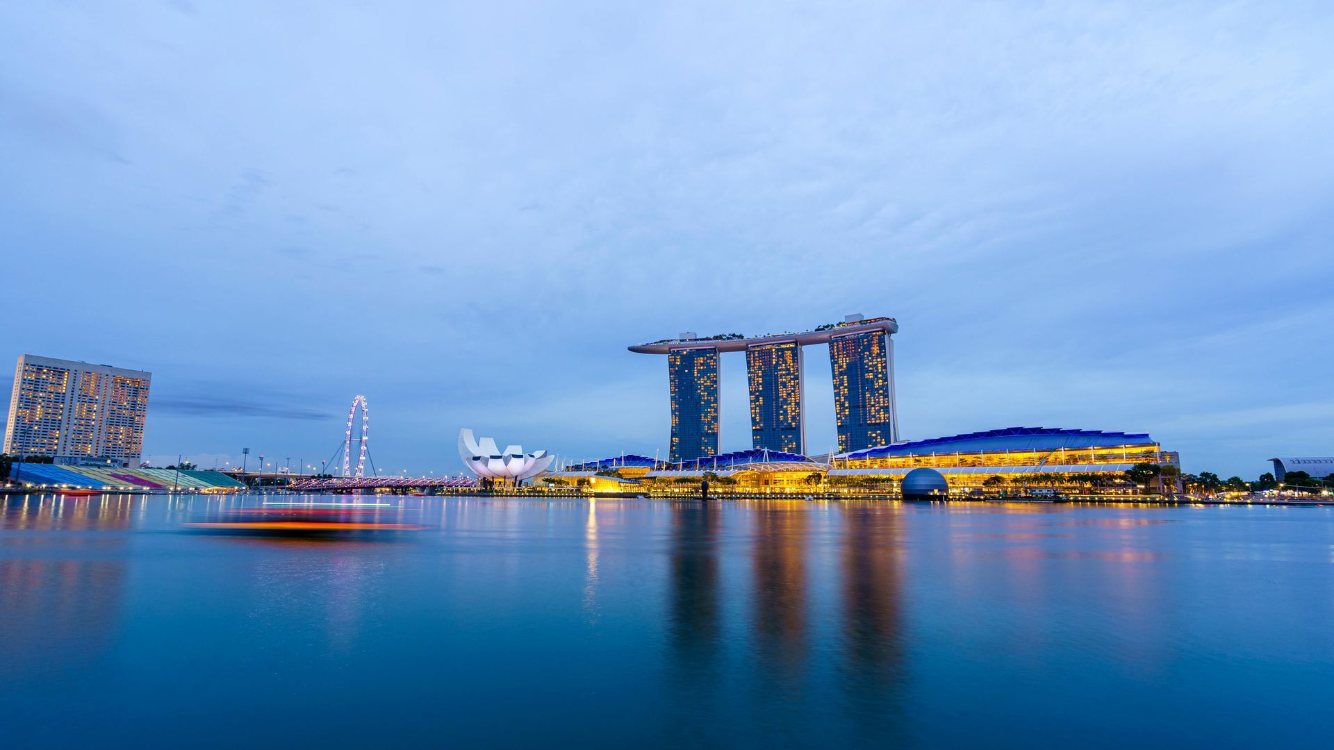 Marina Bay Sands resort in Singapore at twilight, reflected in calm water.