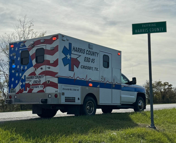 HCESD 5 Ambulance with American flag design parked near a sign for Harris County, Crosby, TX.