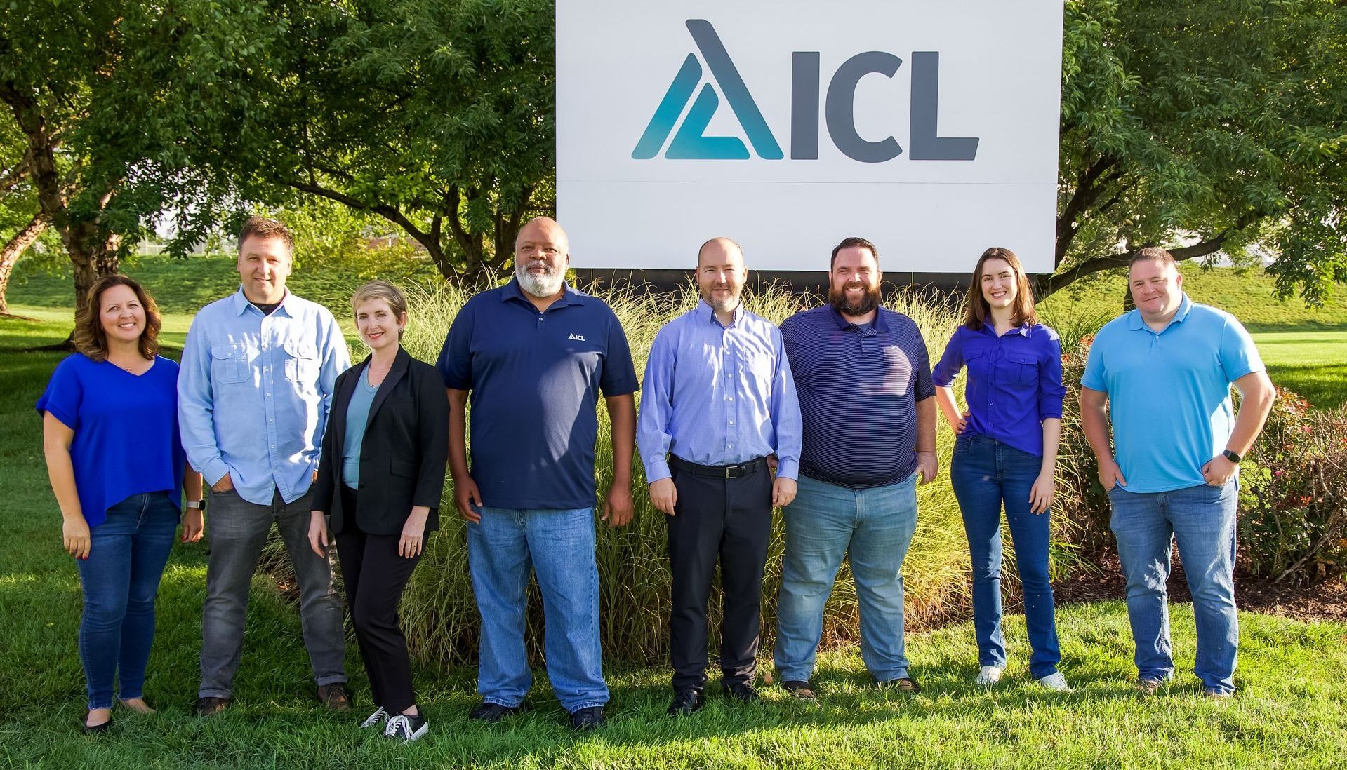 a group of people standing in front of a sign that says icl .