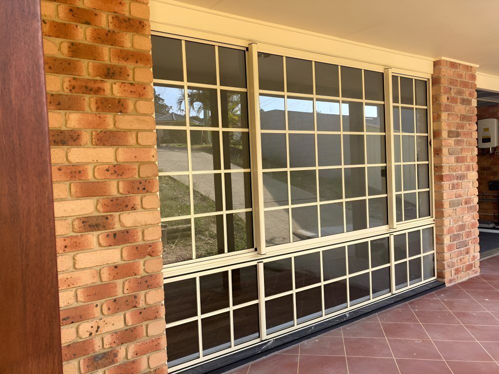 A Large Window with A Brick Wall Behind It — Boambee Gauze 'n' Glass in Harbour, NSW