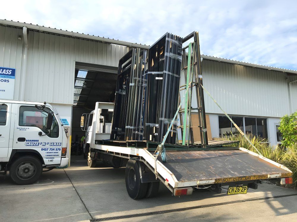 A Tow Truck Is Carrying a Large Stack of Glass — Boambee Gauze 'n' Glass in Harbour, NSW