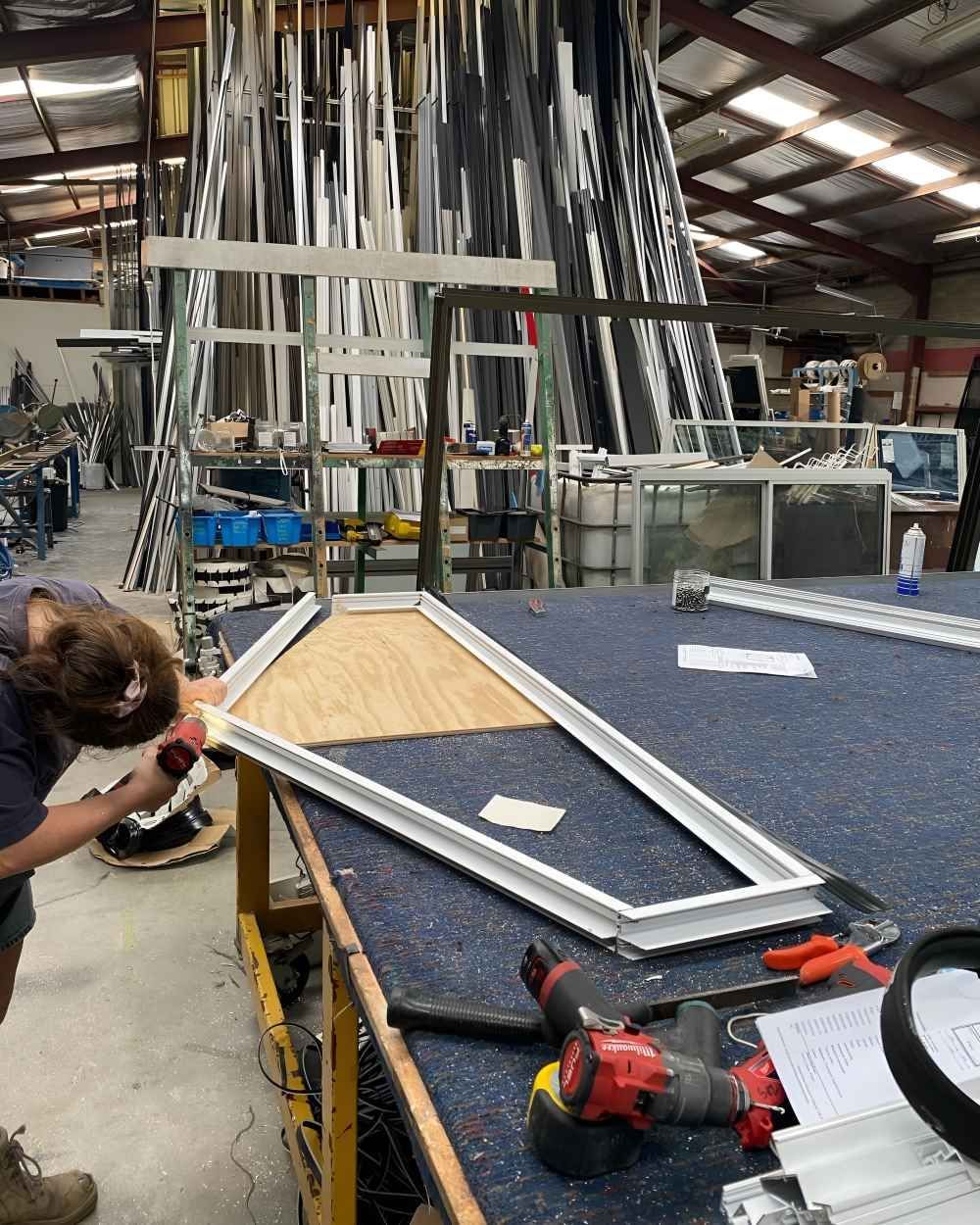 A Woman Is Working on A Frame in A Warehouse — Boambee Gauze 'n' Glass in Harbour, NSW