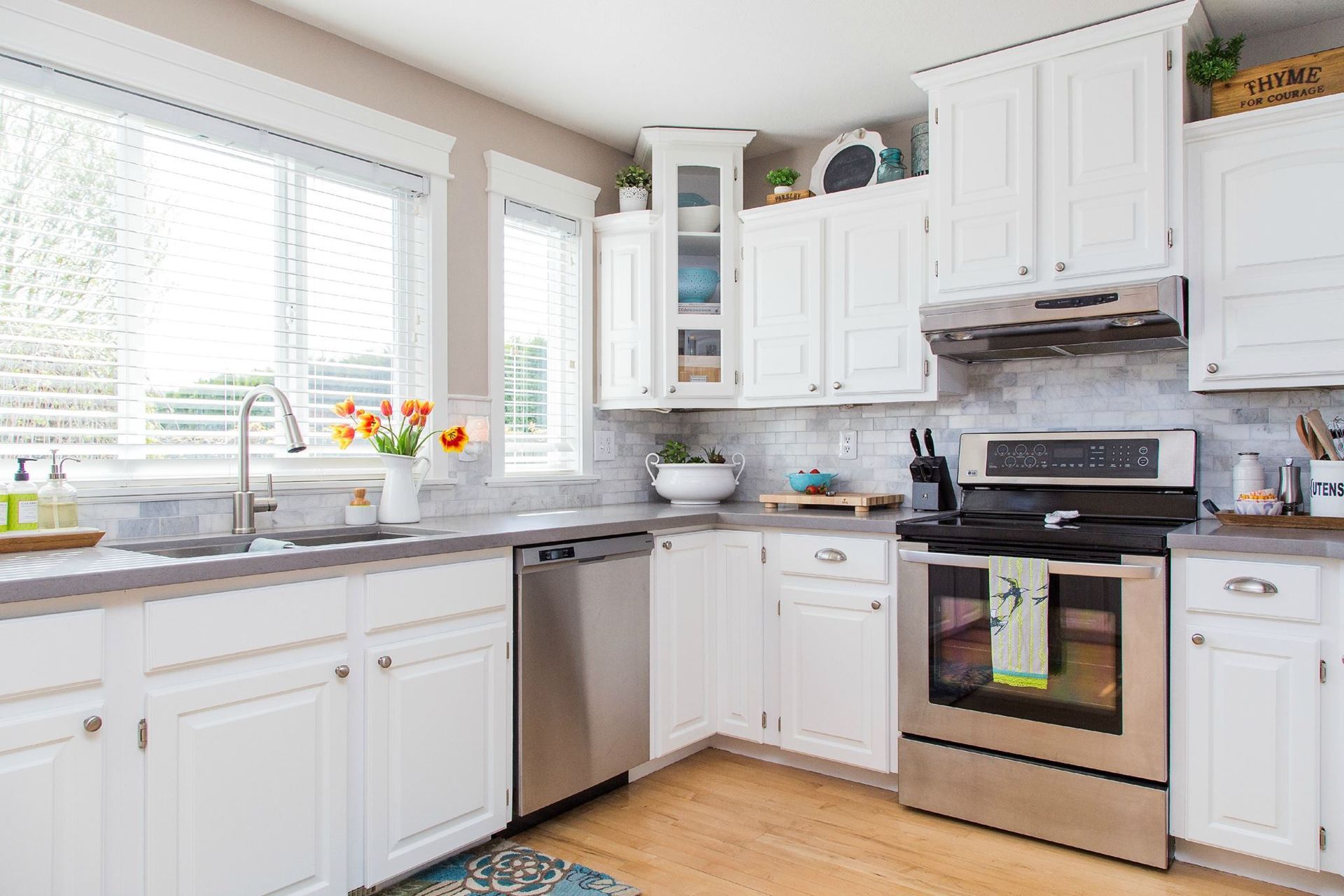 White kitchen with stainless steel appliances, white cabinets, and a window.
