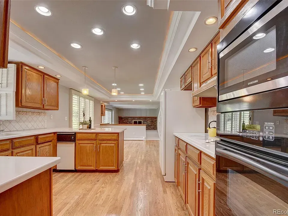 A kitchen with light wood cabinets, white countertops, and stainless steel appliances.
