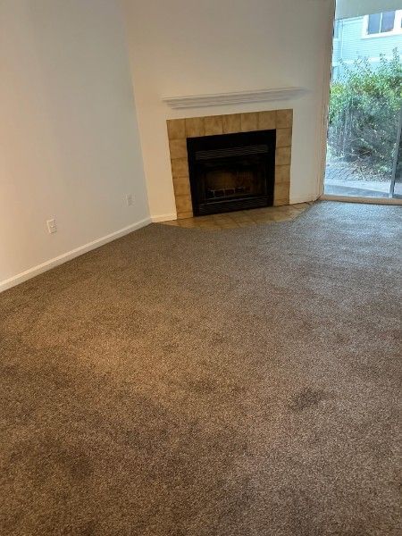Room with brown carpet, fireplace with brick surround, and sliding glass door.