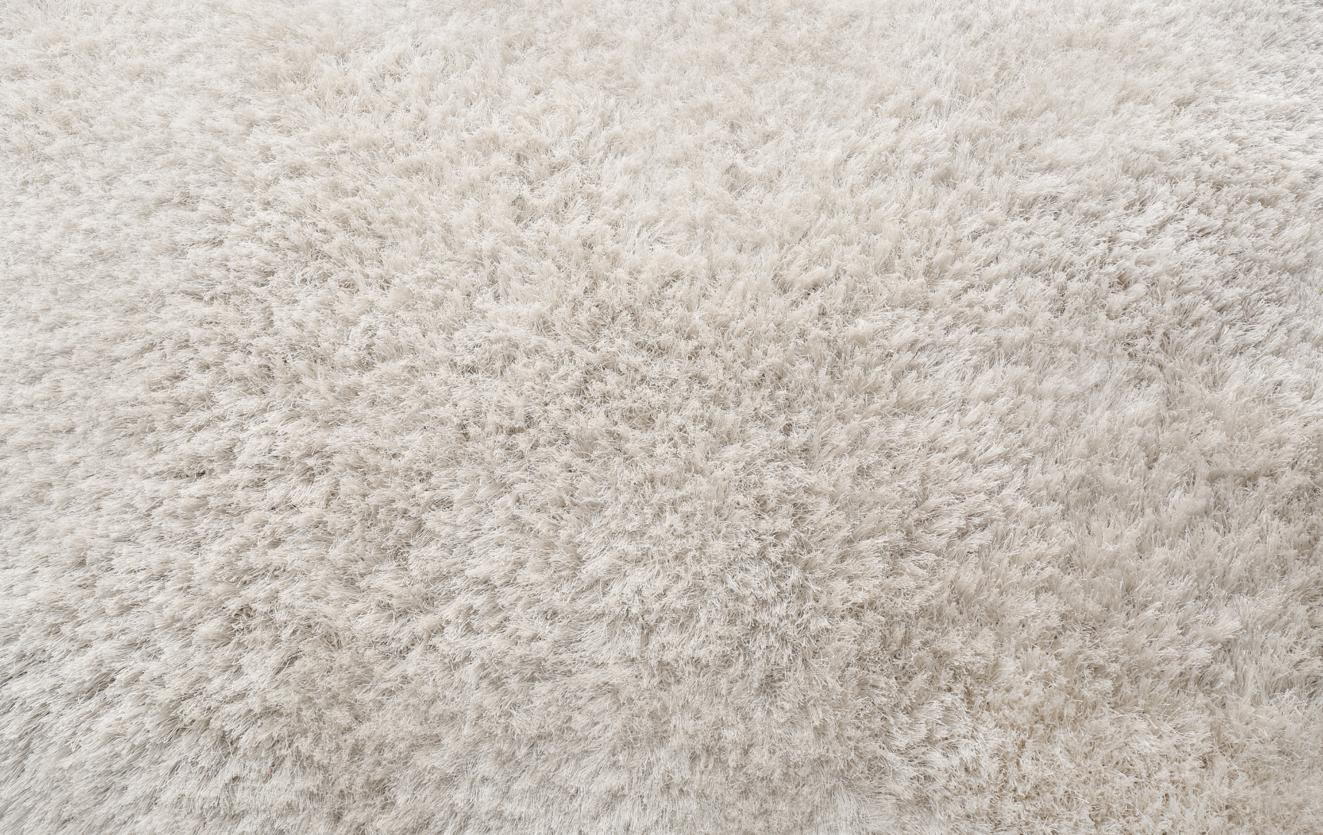Close-up of a textured, light-colored, shaggy carpet.