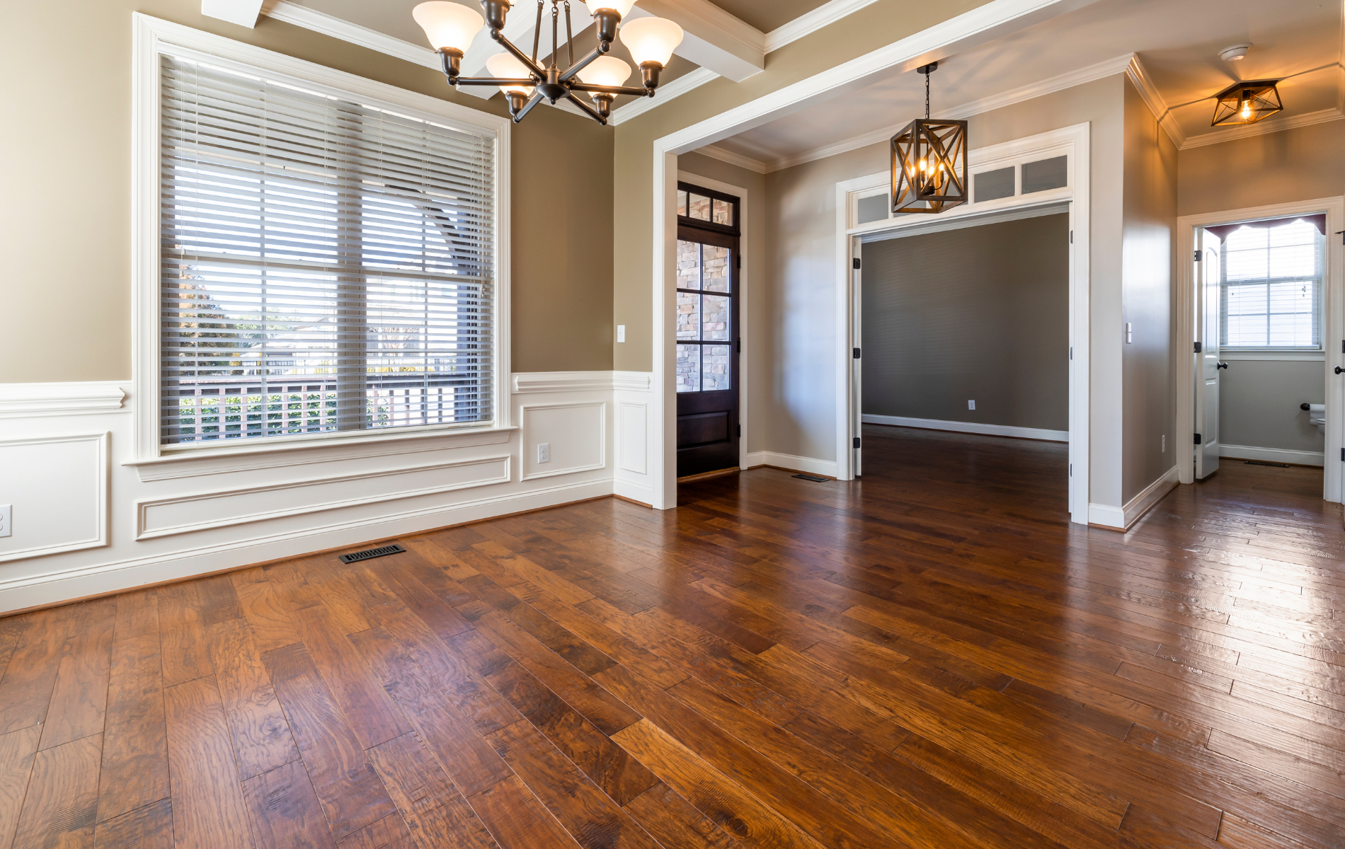 Empty dining room with hardwood floors, white trim, and an open doorway.