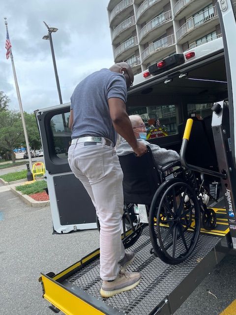 People reviewing documents at a table; others in background; office setting.