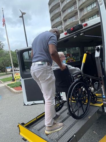People reviewing documents at a table; others in background; office setting.