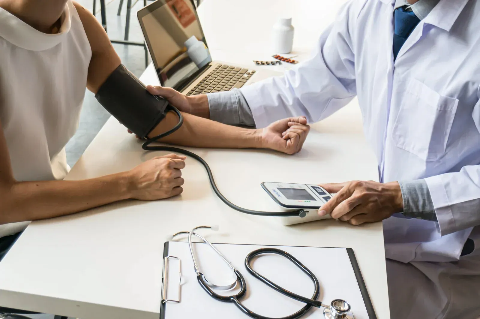 Two-story gray house with garage, lit windows, green lawn, wet street, and dusk sky.
