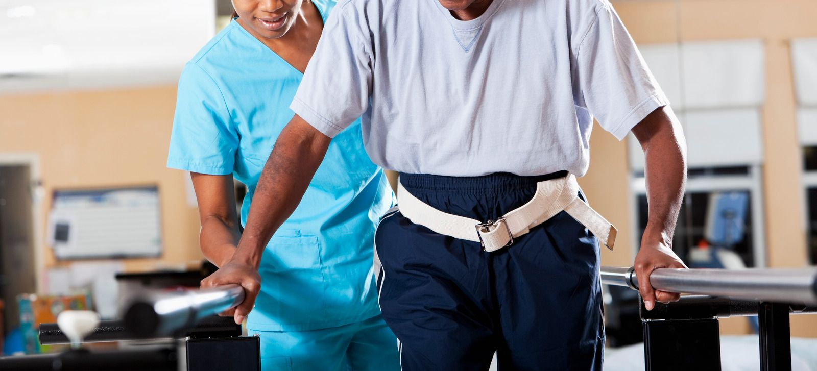 Physical therapist examining a patient's knee. They're in a medical office, and the patient is lying on an examination table.