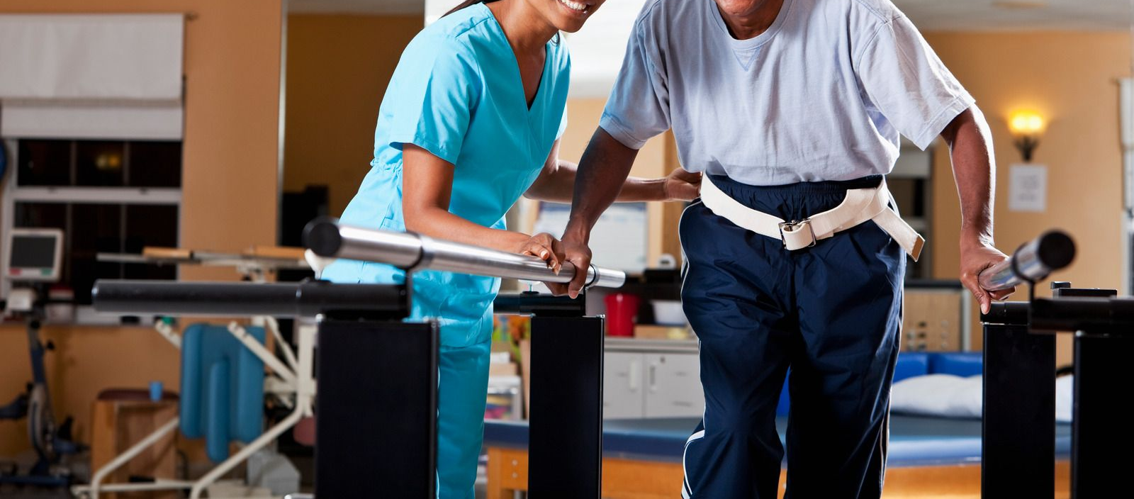 Boy and woman mirroring each other, pointing at their cheeks, in speech therapy session.