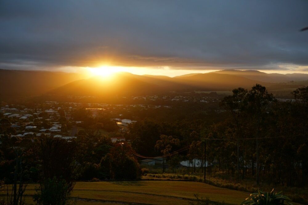 The Sun Is Setting Over A City And Mountains In The Distance — AGB Cleaning In Tablelands, QLD