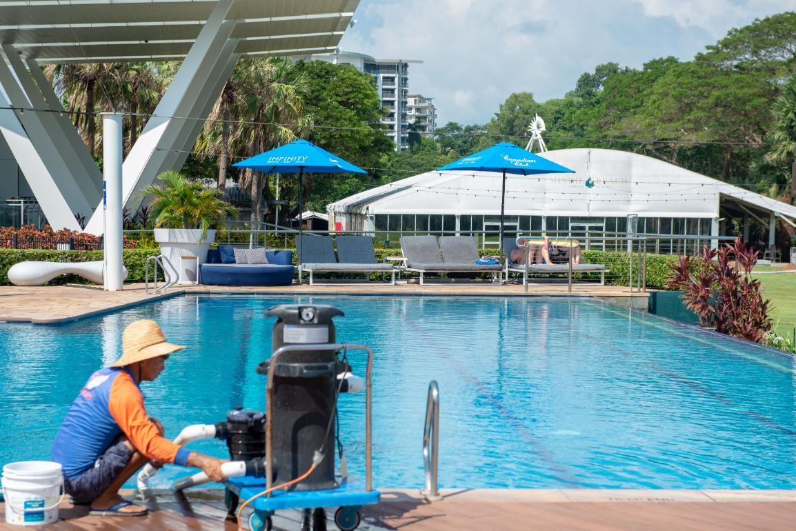 A Man Is Cleaning a Swimming Pool with A Vacuum Cleaner — Figleaf Pool Products in Coconut Grove, NT