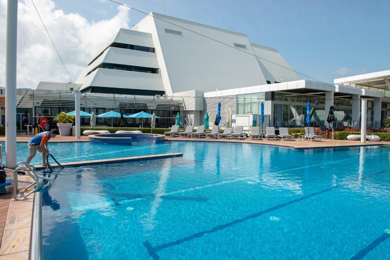 A Man Is Cleaning a Large Swimming Pool with A Vacuum Cleaner — Figleaf Pool Products in Coconut Grove, NT