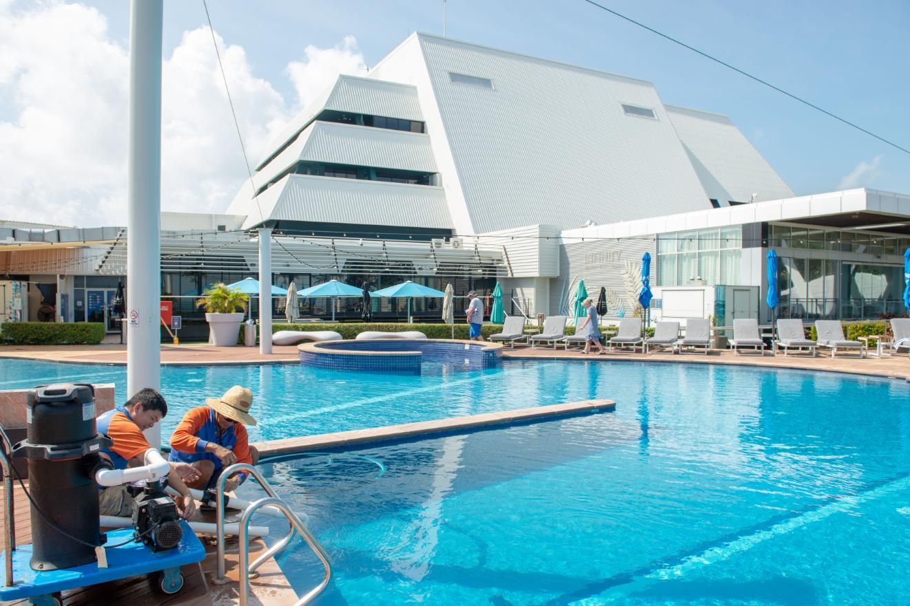 A Large Swimming Pool with A Building in The Background — Figleaf Pool Products in Coconut Grove, NT