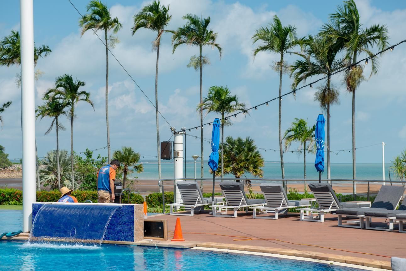 A Swimming Pool Surrounded by Chairs and Palm Trees with A View of The Ocean — Figleaf Pool Products in Coconut Grove, NT