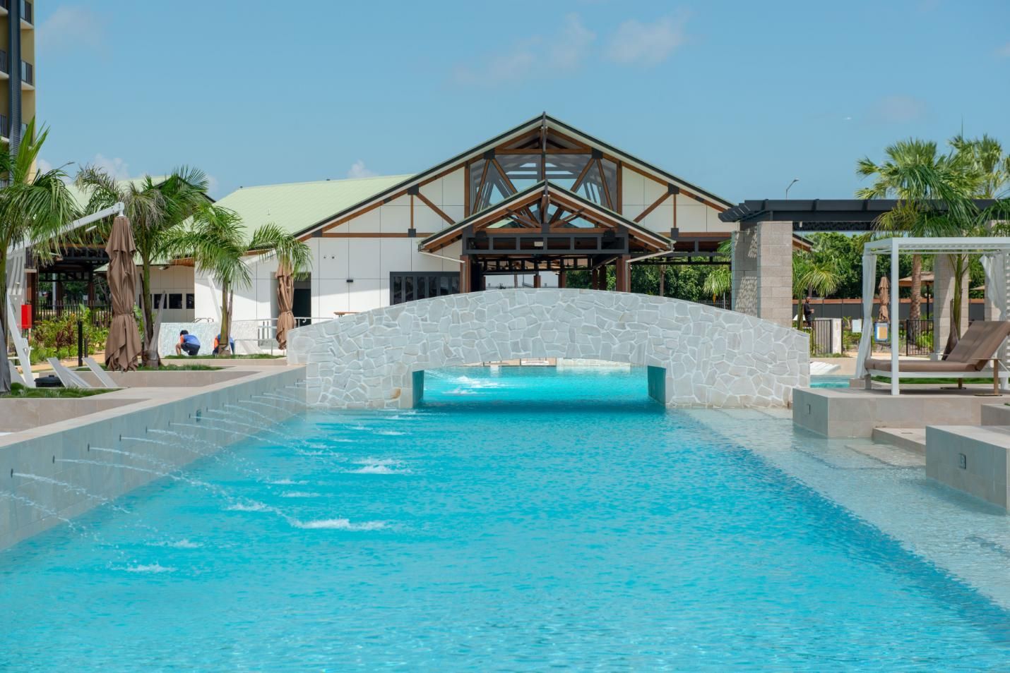 A Large Swimming Pool with A Bridge Over It in Front of A Building — Figleaf Pool Products in Coconut Grove, NT
