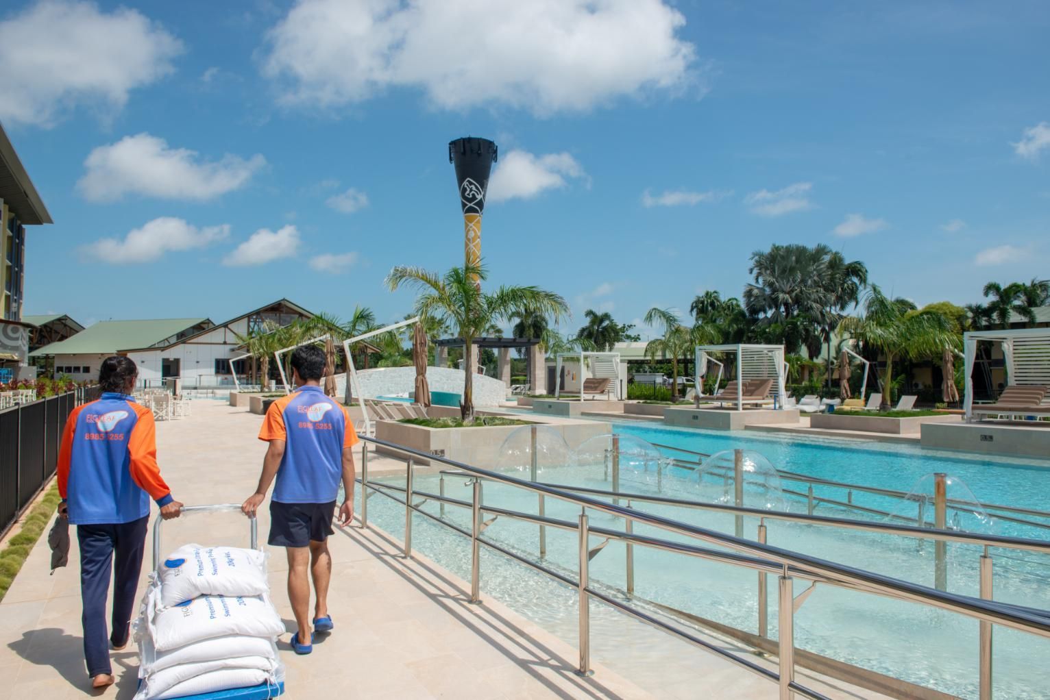 Two People Are Walking Down a Sidewalk Next to A Pool — Figleaf Pool Products in Coconut Grove, NT