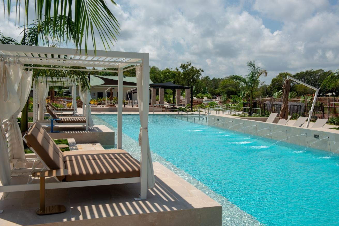 A Large Swimming Pool Surrounded by Rocks and Chairs on A Sunny Day — Figleaf Pool Products in Coconut Grove, NT