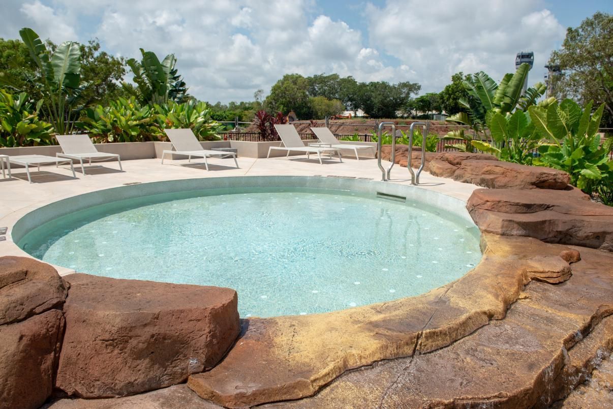 A Large Swimming Pool With a Building in the Background  — Figleaf Pool Products in Coconut Grove, NT