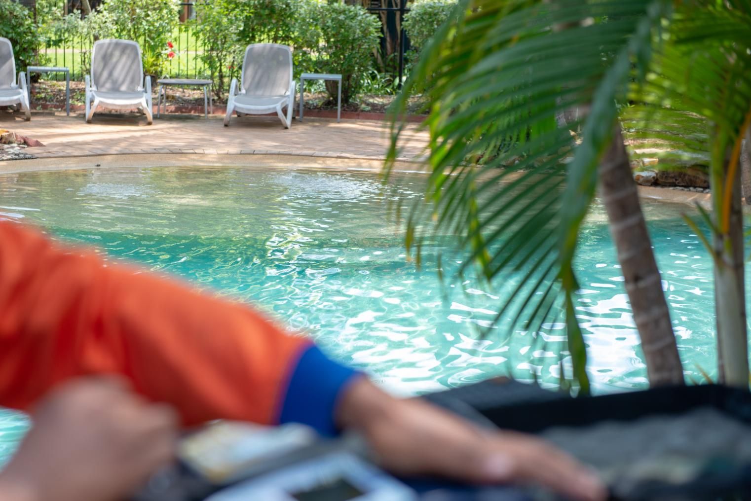 A Man Is Sitting on A Rock Near a Swimming Pool — Figleaf Pool Products in Coconut Grove, NT