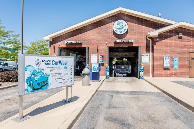 a car is being washed at a car wash in front of a brick building .