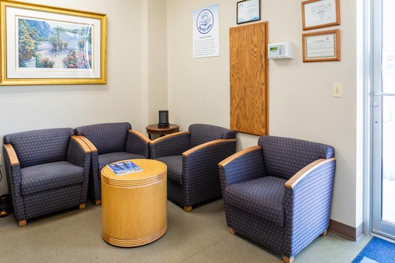 a waiting room with chairs , a table and a picture on the wall .