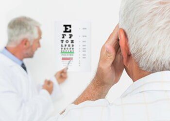 Pediatrician ophthalmologist with senior patient pointing at eye chart — eye exams in Yorktown, VA