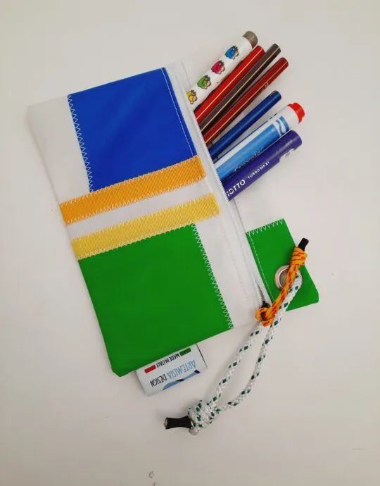 Un astuccio verde blu e giallo pieno di matite e penne