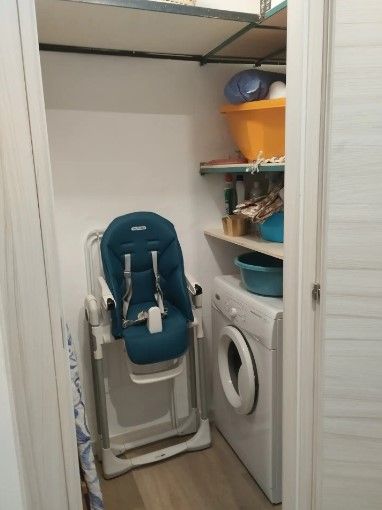 Un seggiolone è seduto in un armadio accanto a una lavatrice e un'asciugatrice.